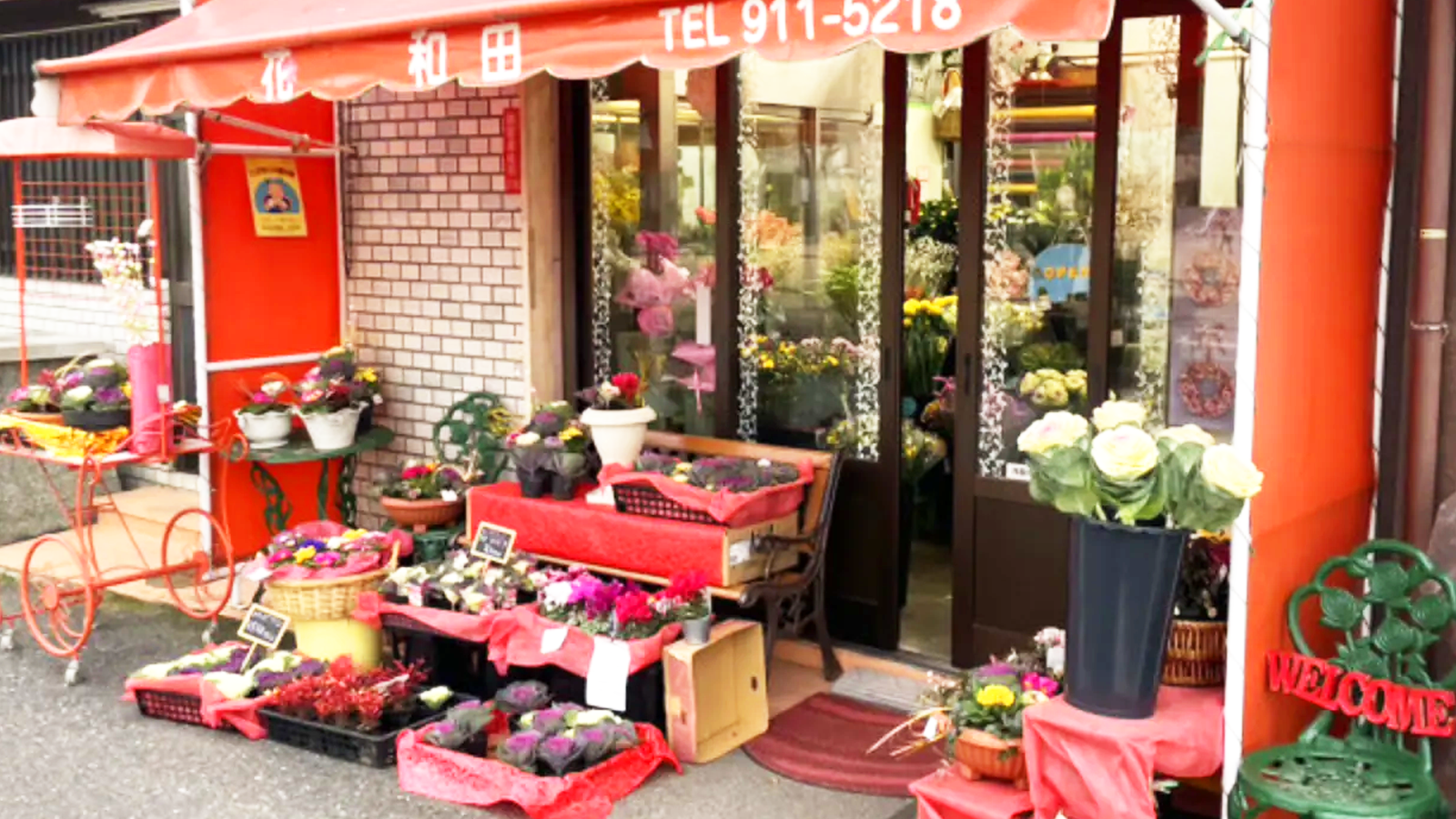 赤いひさしと色とりどりのお花が並ぶ和田生花本店の外観